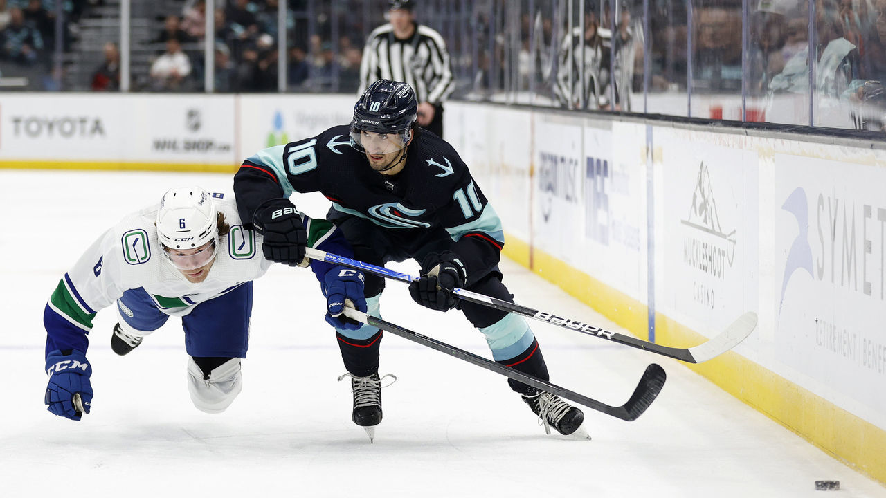 SEATTLE, WASHINGTON - JANUARY 25: Matty Beniers #10 of the Seattle Kraken controls the puck against Brock Boeser #6 of the Vancouver Canucks during the second period at Climate Pledge Arena on January 25, 2023 in Seattle, Washington.