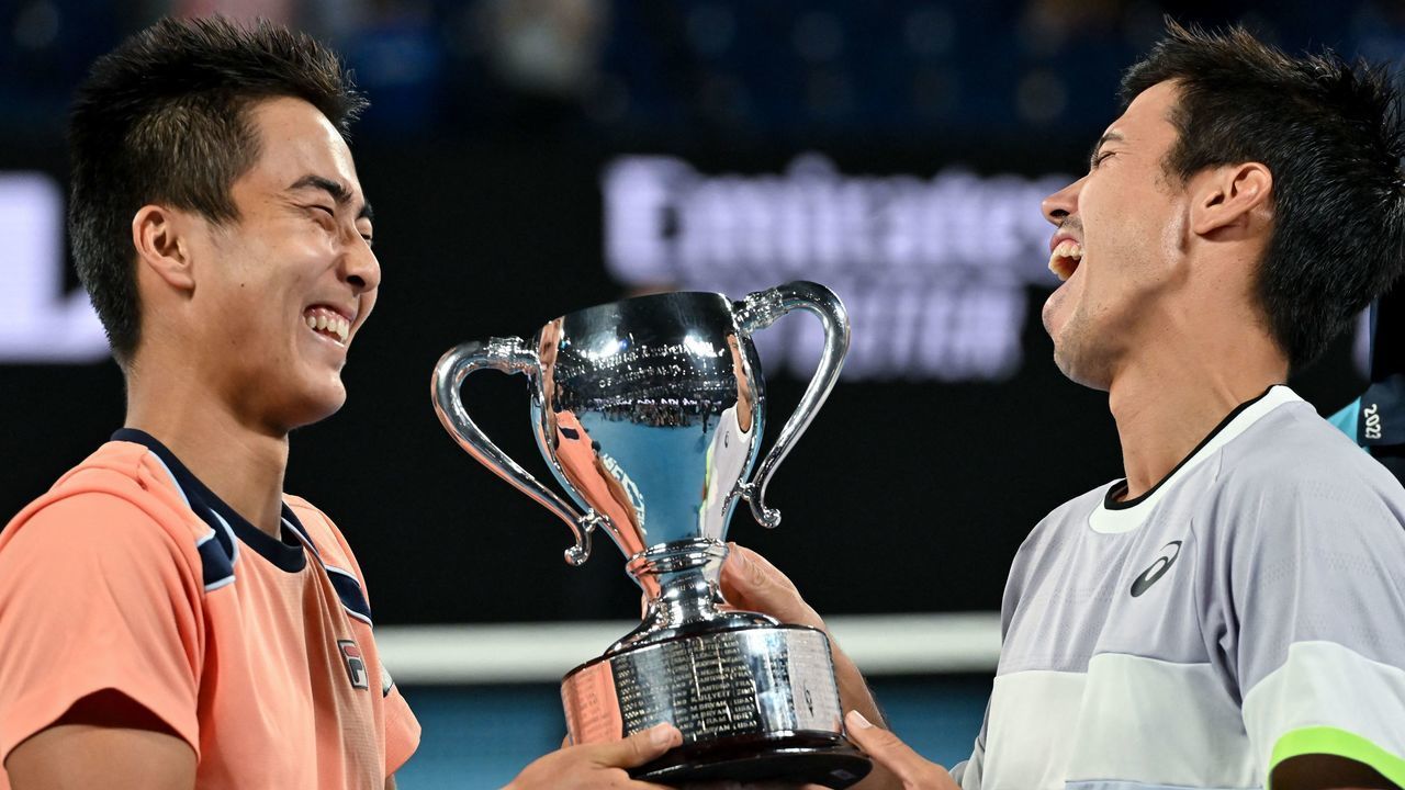 Australia's Rinky Hijikata (L) and Jason Kubler pose with the trophy after victory against Poland's Jan Zielinski and Monaco's Hugo Nys during the men's doubles final on day thirteen of the Australian Open tennis tournament in Melbourne on January 28, 2023. - -- IMAGE RESTRICTED TO EDITORIAL USE - STRICTLY NO COMMERCIAL USE --