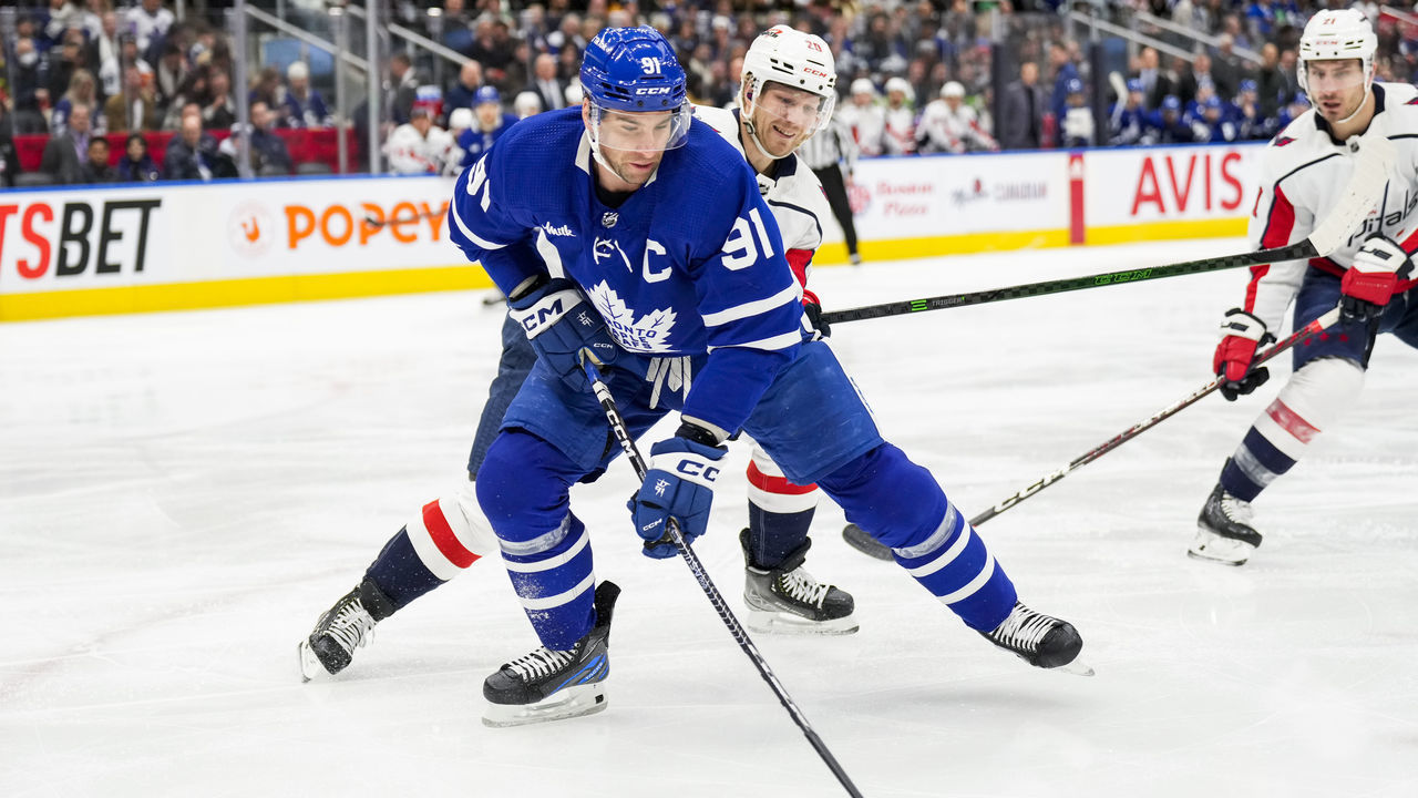 TORONTO, ON - JANUARY 29: John Tavares #91 of the Toronto Maple Leafs plays the puck against Lars Eller #20 of the Washington Capitals during the first period at the Scotiabank Arena on January 29, 2023 in Toronto, Ontario, Canada.