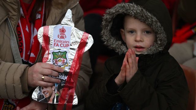 A young Wrexham sits with a home-made trophy as they wait for kick off in the English FA Cup fourth round football match between Wrexham and Sheffield United at the Racecourse Ground Stadium in Wrexham, north Wales, on January 29, 2023. - RESTRICTED TO EDITORIAL USE. No use with unauthorized audio, video, data, fixture lists, club/league logos or 'live' services. Online in-match use limited to 120 images. An additional 40 images may be used in extra time. No video emulation. Social media in-match use limited to 120 images. An additional 40 images may be used in extra time. No use in betting publications, games or single club/league/player publications.