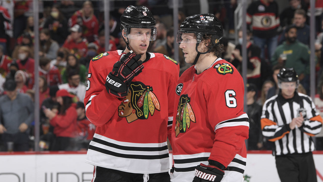 CHICAGO, ILLINOIS - DECEMBER 15: Connor Murphy #5 and Jake McCabe #6 of the Chicago Blackhawks talk during the game against the Washington Capitals at United Center on December 15, 2021 in Chicago, Illinois.
