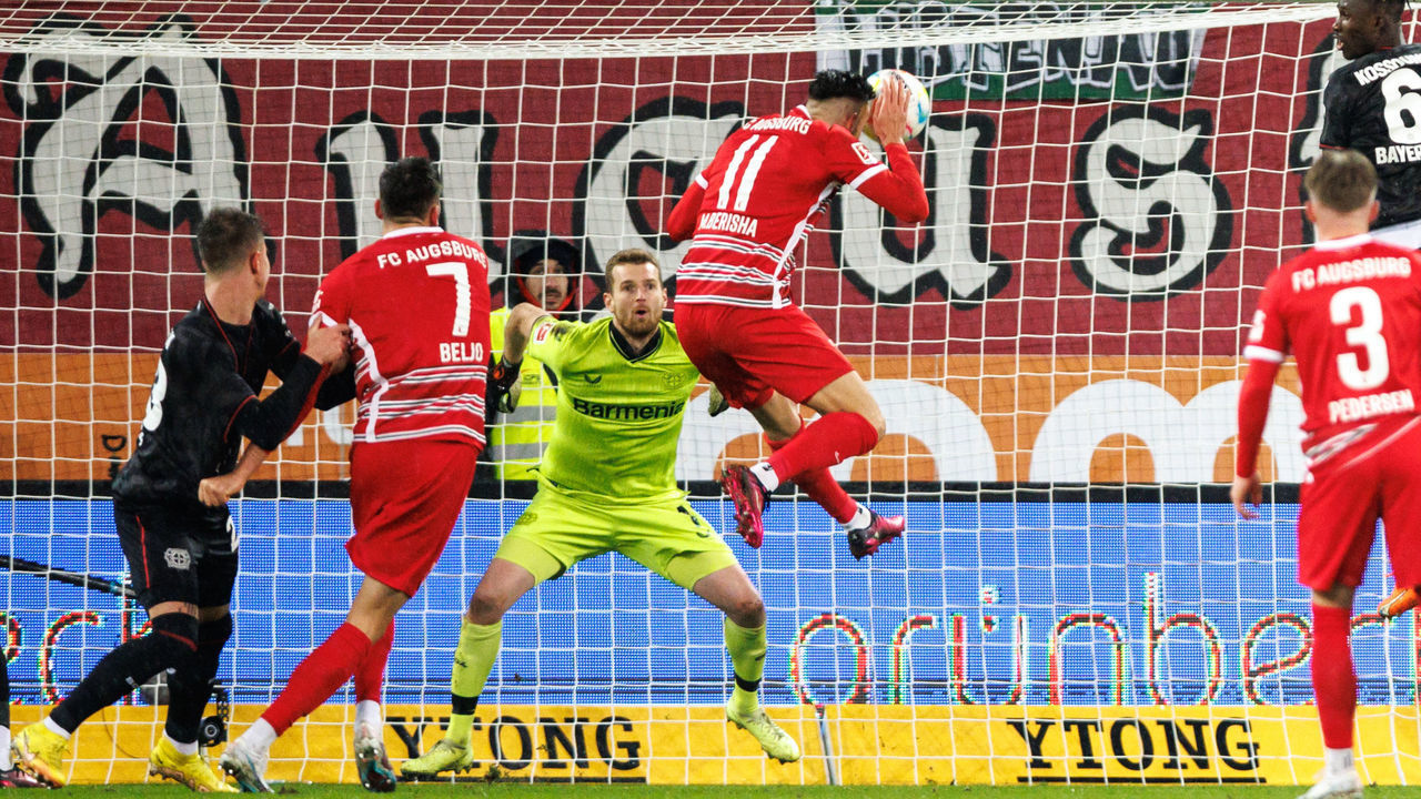 03 February 2023, Bavaria, Augsburg: Soccer: Bundesliga, FC Augsburg - Bayer Leverkusen, Matchday 19, WWK Arena. FC Augsburg's Mergim Berisha (r) scores to make it 1:0. Bayer Leverkusen goalkeeper Lukas Hradecky, left, cannot keep out the ball. Photo: Matthias Balk/dpa - IMPORTANT NOTE: In accordance with the requirements of the DFL Deutsche Fußball Liga and the DFB Deutscher Fußball-Bund, it is prohibited to use or have used photographs taken in the stadium and/or of the match in the form of sequence pictures and/or video-like photo series.