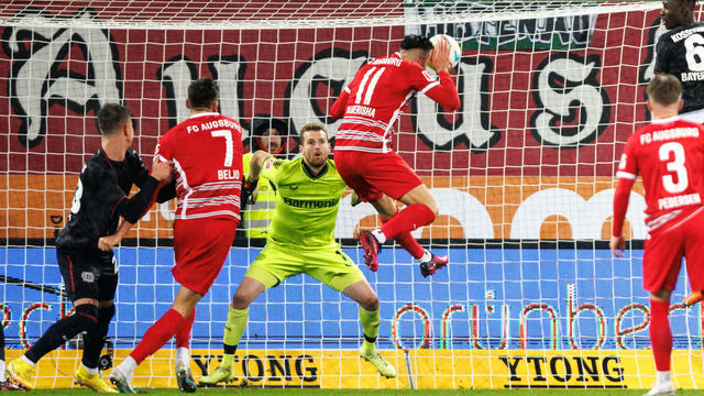 03 February 2023, Bavaria, Augsburg: Soccer: Bundesliga, FC Augsburg - Bayer Leverkusen, Matchday 19, WWK Arena. FC Augsburg's Mergim Berisha (r) scores to make it 1:0. Bayer Leverkusen goalkeeper Lukas Hradecky, left, cannot keep out the ball. Photo: Matthias Balk/dpa - IMPORTANT NOTE: In accordance with the requirements of the DFL Deutsche Fußball Liga and the DFB Deutscher Fußball-Bund, it is prohibited to use or have used photographs taken in the stadium and/or of the match in the form of sequence pictures and/or video-like photo series.