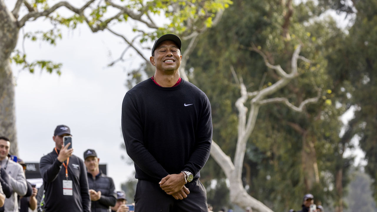 PACIFIC PALISADES, CA - FEBRUARY 20, 2022: Tournament host Tiger Woods takes in the moment as winner Joaquin Niemann holds the trophy after the final round of the Genesis Invitational at Riviera Country Club on February 20, 2022 in Pacific Palisades, California.One year ago, Woods was involved in a car accident the day after the tournament.(Gina Ferazzi / Los Angeles Times via Getty Images)