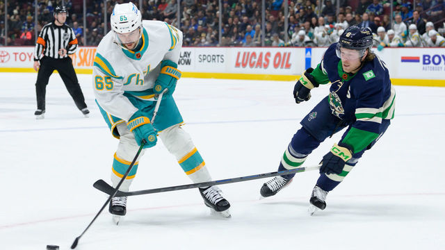 VANCOUVER, CANADA - DECEMBER 27: Brock Boeser #6 of the Vancouver Canucks defends against Erik Karlsson #65 of the San Jose Sharks during the first period of their NHL game at Rogers Arena on December 27, 2022 in Vancouver, British Columbia, Canada.
