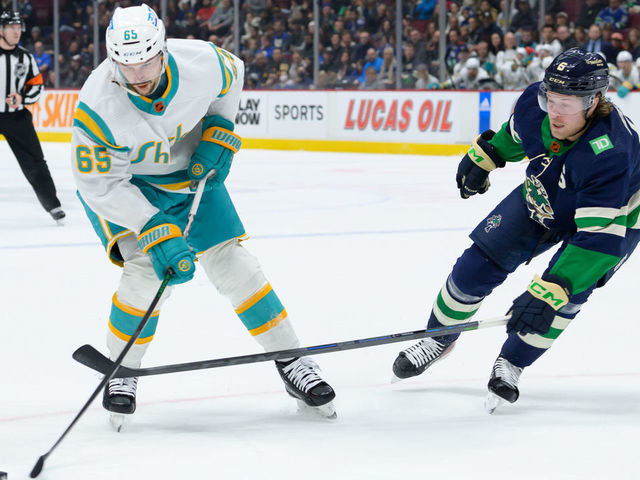 VANCOUVER, CANADA - DECEMBER 27: Brock Boeser #6 of the Vancouver Canucks defends against Erik Karlsson #65 of the San Jose Sharks during the first period of their NHL game at Rogers Arena on December 27, 2022 in Vancouver, British Columbia, Canada.
