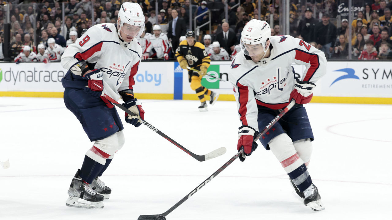 BOSTON, MA - FEBRUARY 11: Washington Capitals right wing Garnet Hathaway (21) grabs the puck watched by defenseman Dmitry Orlov (9) during a game between the Boston Bruins and the Washington Capitals on February 11, 2023, at TD Garden in Boston, Massachusetts.