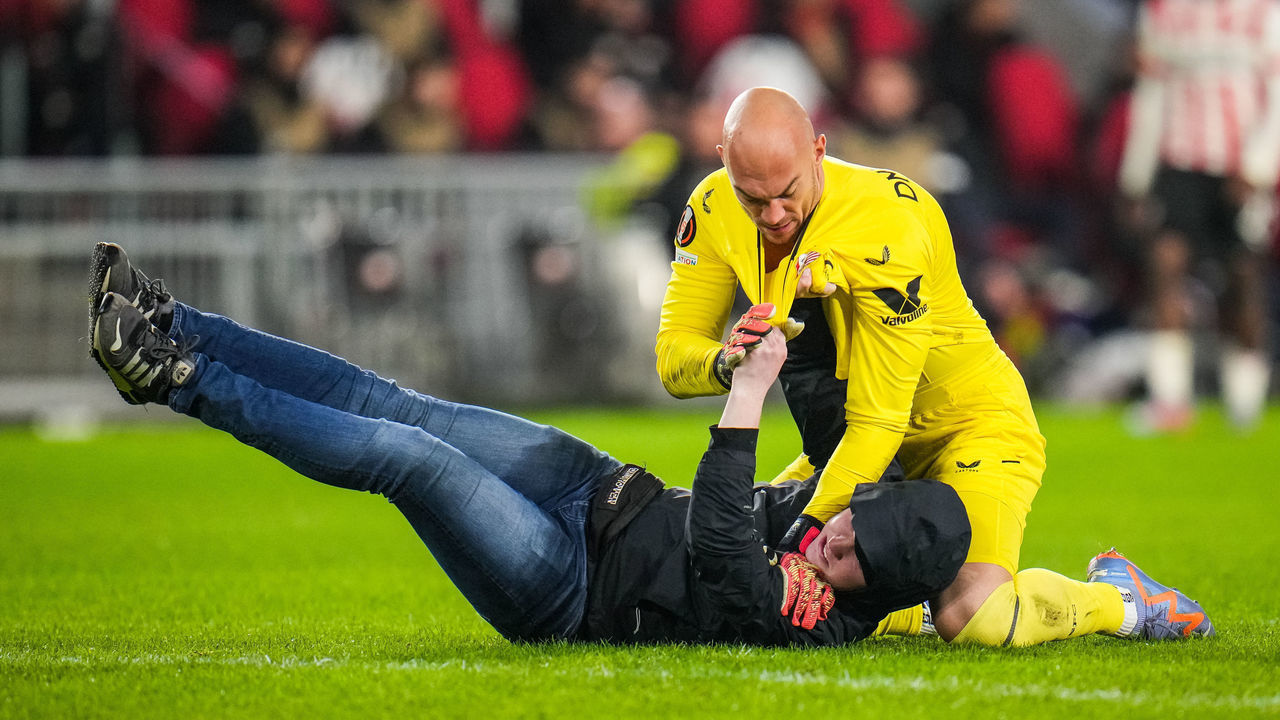 EINDHOVEN, NETHERLANDS - FEBRUARY 23: Marko Dmitrovic of Sevilla FC fights with a supporter who invaded the pitch during the UEFA Europa League Knockout Round Play-Off Leg Two match between PSV and Sevilla FC at the Philips Stadion on February 23, 2023 in Eindhoven, Netherlands