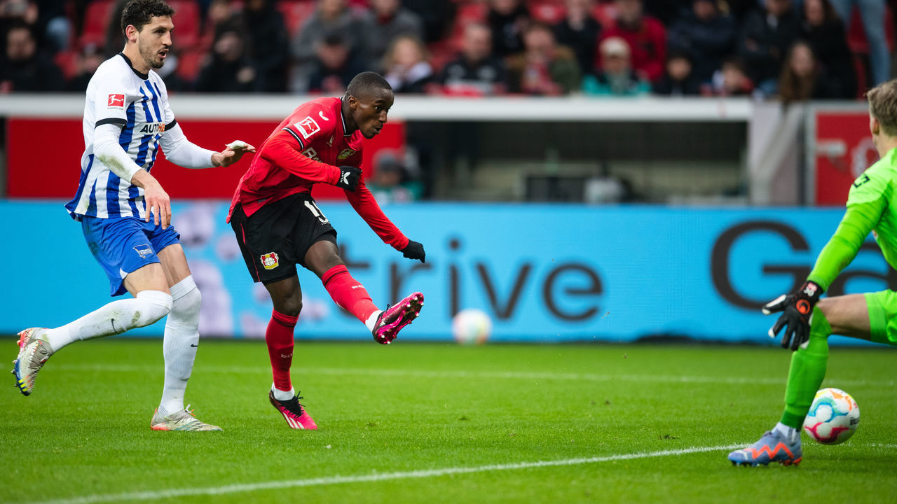 05 March 2023, North Rhine-Westphalia, Leverkusen: Soccer: Bundesliga, Bayer Leverkusen - Hertha BSC, Matchday 23, BayArena. Leverkusen's Moussa Diaby (M) scores against Hertha goalkeeper Oliver Christensen (r) and Agustin Rogel (l) to make it 3:0. Photo: Marius Becker/dpa - IMPORTANT NOTE: In accordance with the requirements of the DFL Deutsche Fußball Liga and the DFB Deutscher Fußball-Bund, it is prohibited to use or have used photographs taken in the stadium and/or of the match in the form of sequence pictures and/or video-like photo series.
