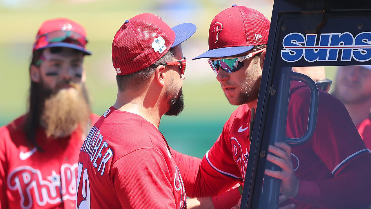 CLEARWATER, FL - March 23: Philadelphia Phillies Left fielder Kyle Schwarber (12) helps First baseman Rhys Hoskins (17) sit down in the cart during the spring training game between the Toronto Blue Jays and the Detroit Tigers on March 23, 2023 at BayCare Ballpark in Clearwater, Florida.