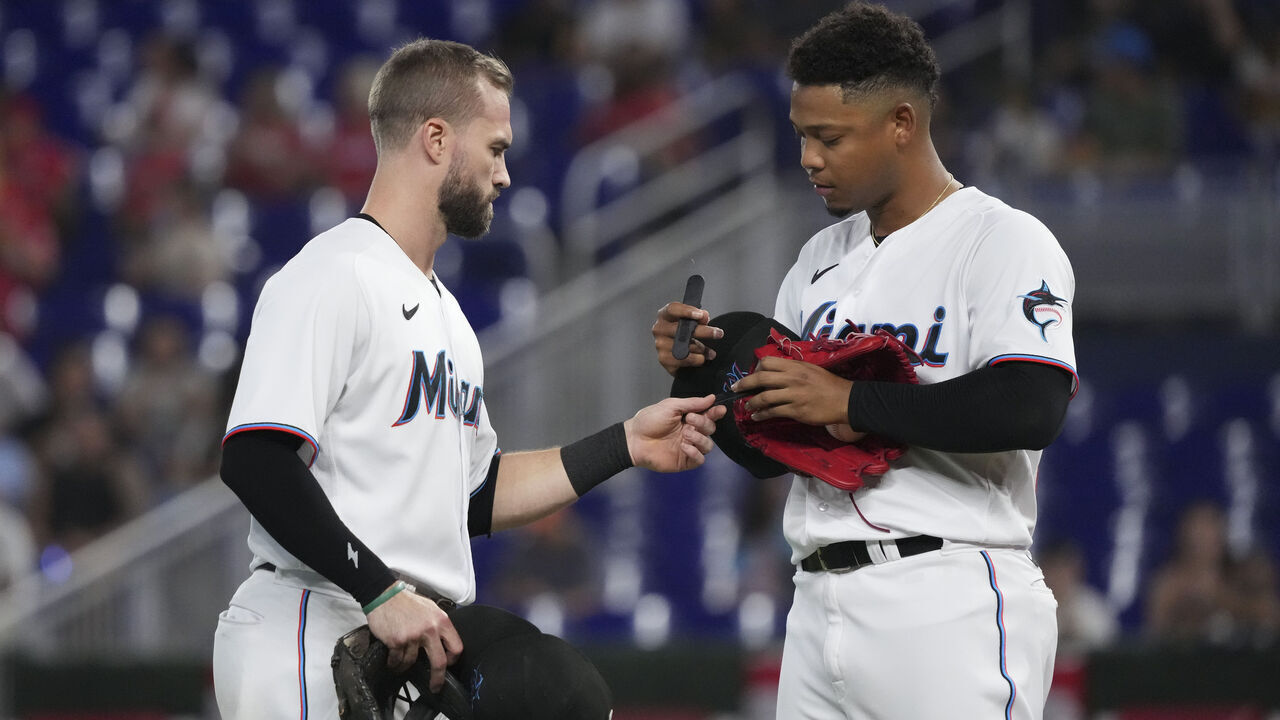 MIAMI, FLORIDA - OCTOBER 05: Jon Berti #5 of the Miami Marlins exchanges pitchcom devices with Elieser Hernandez #57 during the second inning of the game against the Atlanta Braves at loanDepot park on October 05, 2022 in Miami, Florida.