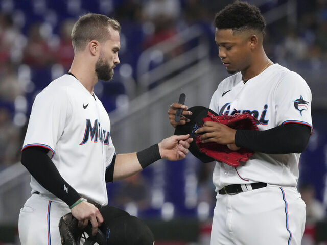 MIAMI, FLORIDA - OCTOBER 05: Jon Berti #5 of the Miami Marlins exchanges pitchcom devices with Elieser Hernandez #57 during the second inning of the game against the Atlanta Braves at loanDepot park on October 05, 2022 in Miami, Florida.