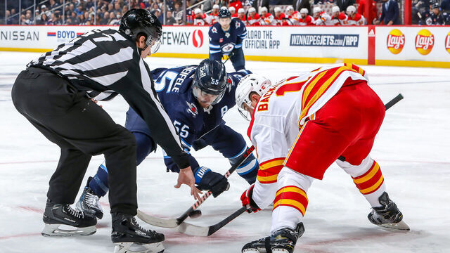WINNIPEG, CANADA - JANUARY 3: Mark Scheifele #55 of the Winnipeg Jets takes a second period face-off against Mikael Backlund #11 of the Calgary Flames at the Canada Life Centre on January 3, 2023 in Winnipeg, Manitoba, Canada.