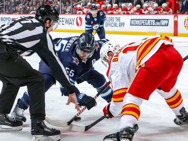 WINNIPEG, CANADA - JANUARY 3: Mark Scheifele #55 of the Winnipeg Jets takes a second period face-off against Mikael Backlund #11 of the Calgary Flames at the Canada Life Centre on January 3, 2023 in Winnipeg, Manitoba, Canada.