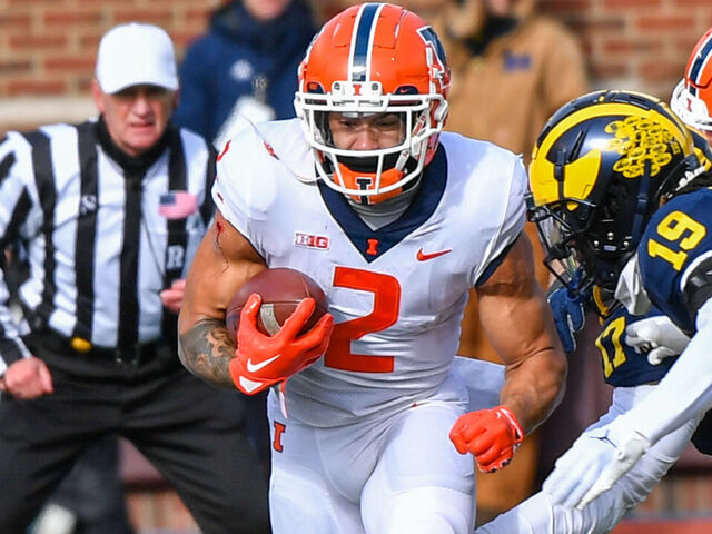 ANN ARBOR, MICHIGAN - NOVEMBER 19: Chase Brown #2 of the Illinois Fighting Illini runs with the ball against Rod Moore #19 of the Michigan Wolverines during the first half at Michigan Stadium on November 19, 2022 in Ann Arbor, Michigan.