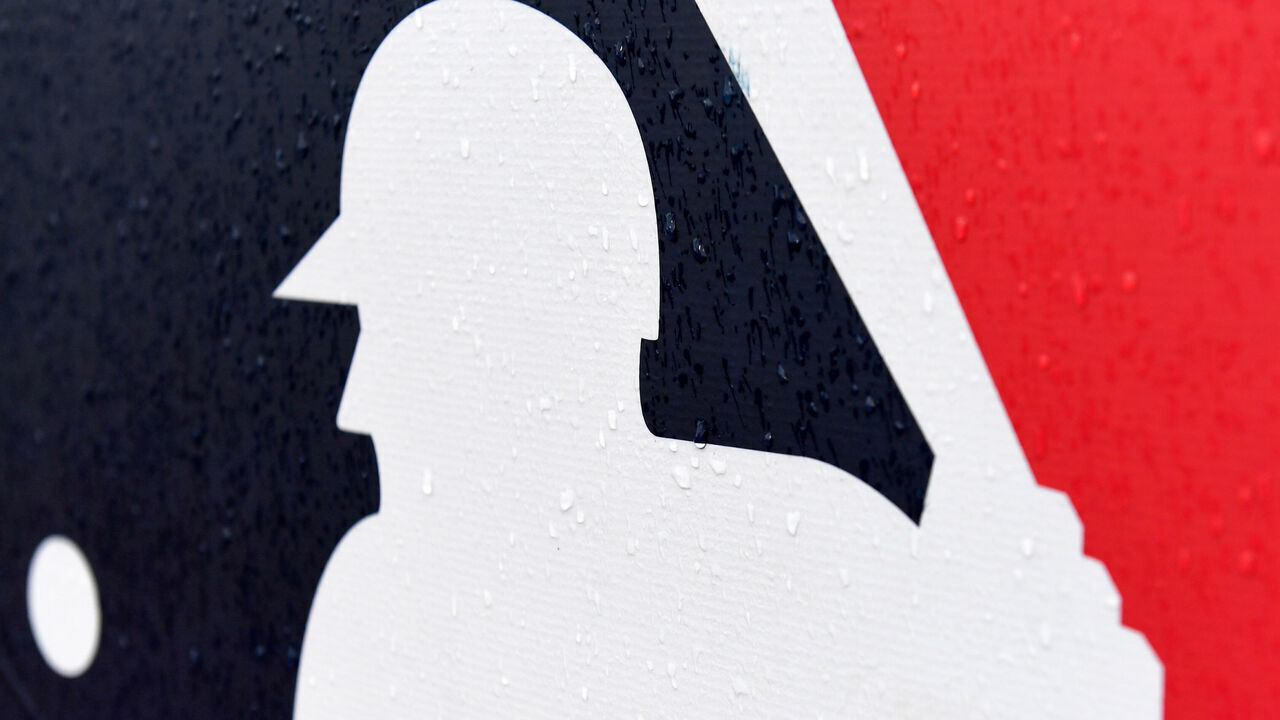 CLEVELAND, OH - AUGUST 21: A closeup view of the Major League Baseball logo as rain falls prior to a game between the Chicago White Sox and the Cleveland Guardians at Progressive Field on August 21, 2022 in Cleveland, Ohio. The game was postponed due to unsafe field conditions.
