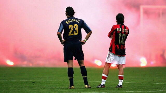 MILAN, ITALY - APRIL 12: Marco Materazzi of Inter Milan and Rui Costa of AC Milan look on as Inter fans shower the pitch with flares during the UEFA Champions League quarter-final second leg between AC Milan and Inter Milan at the San Siro Stadium on April 12, 2005 in Milan, Italy.