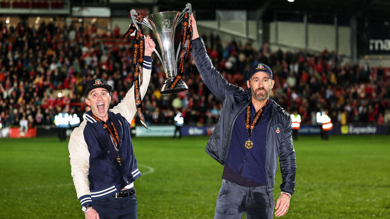 WREXHAM, WALES - APRIL 22: Ryan Reynolds co-owner of Wrexham and Rob McElhenney co-owner of Wrexham with the Vanarama National League Trophy as Wrexham celebrate promotion back to the English Football League during the Vanarama National League match between Wrexham and Boreham Wood at Racecourse Ground on April 22, 2023 in Wrexham, Wales.