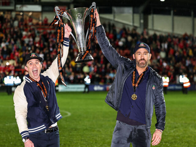 WREXHAM, WALES - APRIL 22: Ryan Reynolds co-owner of Wrexham and Rob McElhenney co-owner of Wrexham with the Vanarama National League Trophy as Wrexham celebrate promotion back to the English Football League during the Vanarama National League match between Wrexham and Boreham Wood at Racecourse Ground on April 22, 2023 in Wrexham, Wales.