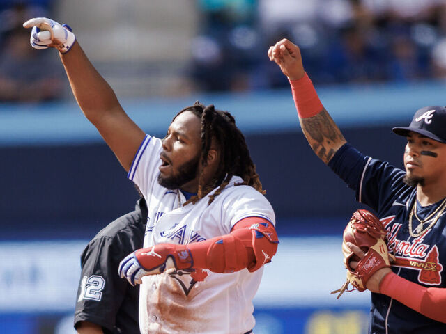 TORONTO, ON - MAY 13: Vladimir Guerrero Jr. #27 of the Toronto Blue Jays reacts as he takes second base in front of Orlando Arcia #11 of the Atlanta Braves in the fourth inning at Rogers Centre on May 13, 2023 in Toronto, Canada.