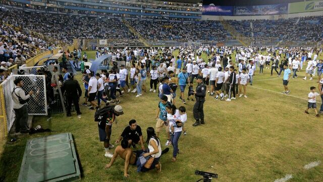TOPSHOT - Supporters are helped by others following a stampede during a football match between Alianza and FAS at Cuscatlan stadium in San Salvador, on May 20, 2023. Nine people were killed May 20, 2023 in a stampede at an El Salvador stadium where soccer fans had gathered to watch a local tournament, police said.