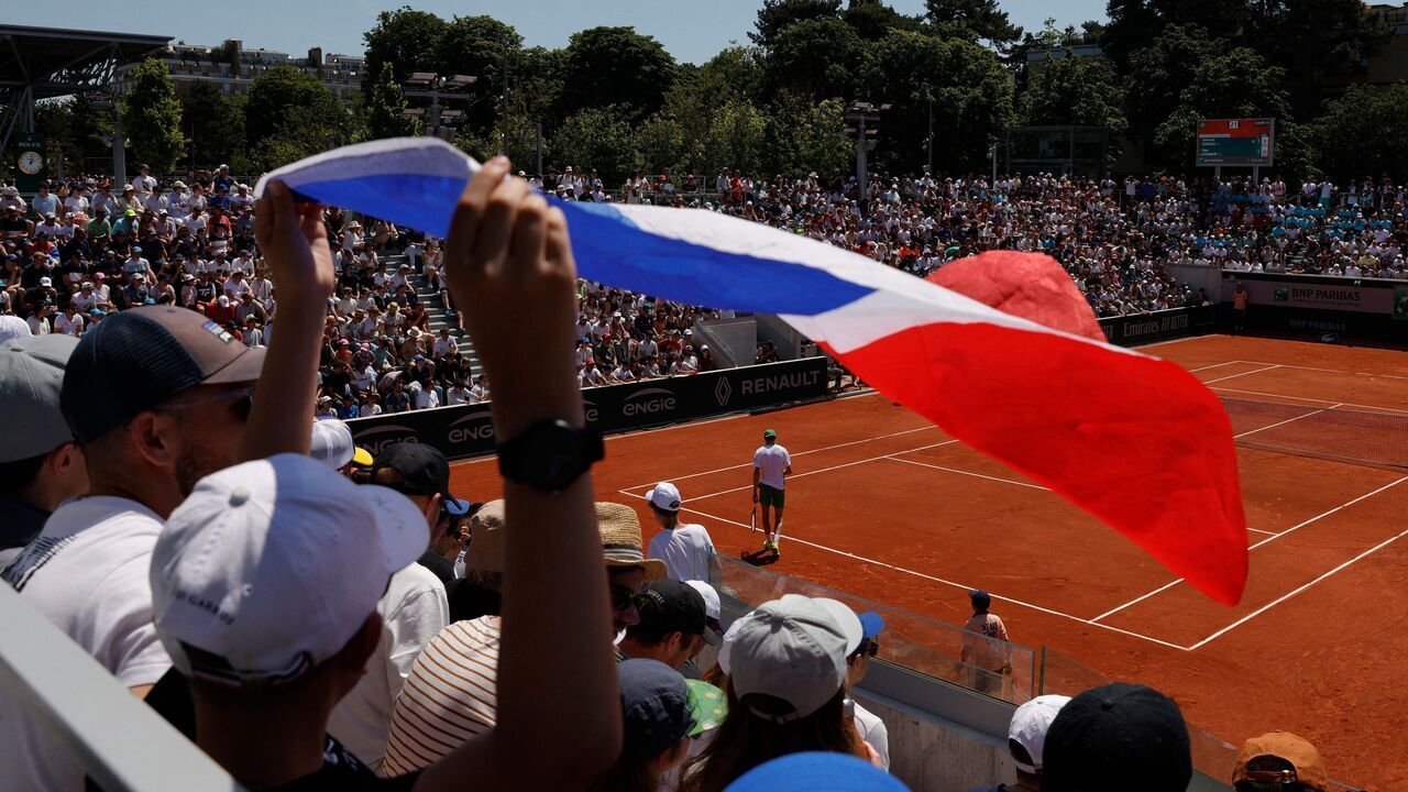 TOPSHOT - A Spectator holds a French flag as he watches the men's singles match between France's Ugo Humbert and Italy's Lorenzo Sonego on day four of the Roland-Garros Open tennis tournament in Paris on May 31, 2023.