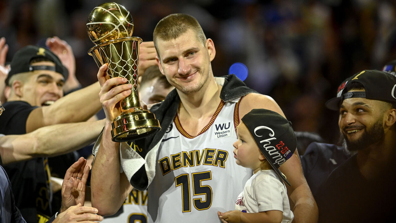 DENVER, CO - JUNE 12: Nikola Jokic (15) of the Denver Nuggets displays the NBA Finals Most Valuable Player Award as the star holds his daughter, Ognjena, after the fourth quarter of the Nuggets' 94-89 NBA Finals clinching win over the Miami Heat at Ball Arena in Denver on Monday, June 12, 2023.