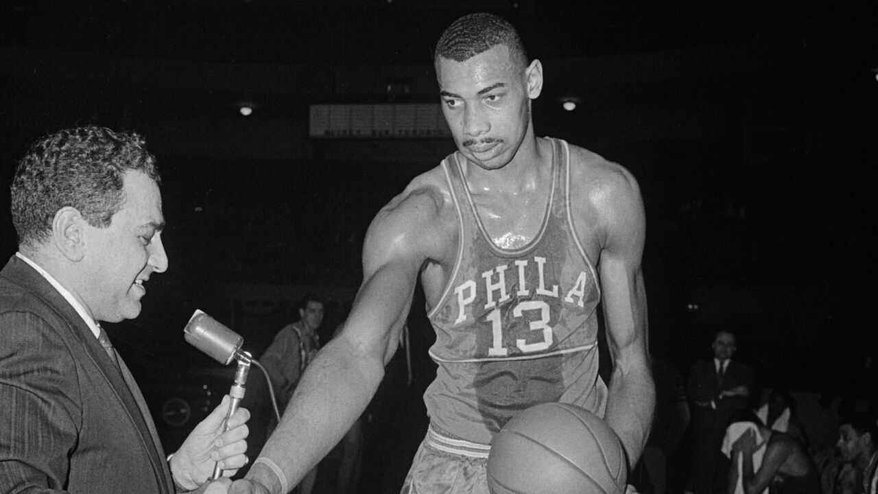(Original Caption) Detroit: Wilt Chamberlain, of the Philadelphia Warriors, accepts the congratulations of Detroit Pistons General Manager Nick Kerbawy (left) and the ball with which he broke the N.B.A. individual scoring record of 2,105 points during the Detroit-Philadelphia game.