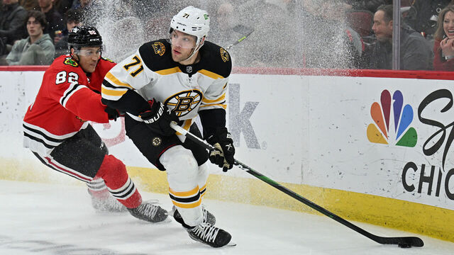 CHICAGO, ILLINOIS - MARCH 15: Taylor Hall #71 of the Boston Bruins controls the puck in front of Caleb Jones #82 of the Chicago Blackhawks in the third period on March 15, 2022 at the United Center in Chicago, Illinois. Boston defeated Chicago 2-1 in overtime.