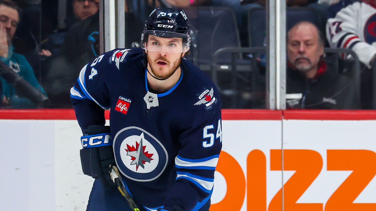 WINNIPEG, CANADA - APRIL 10: Dylan Samberg #54 of the Winnipeg Jets plays the puck during second period action against the San Jose Sharks at Canada Life Centre on April 10, 2023 in Winnipeg, Manitoba, Canada.