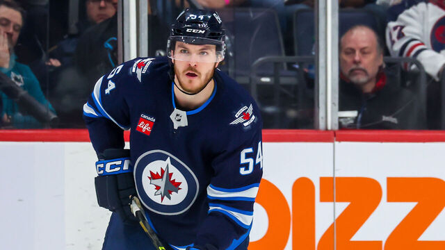 WINNIPEG, CANADA - APRIL 10: Dylan Samberg #54 of the Winnipeg Jets plays the puck during second period action against the San Jose Sharks at Canada Life Centre on April 10, 2023 in Winnipeg, Manitoba, Canada.