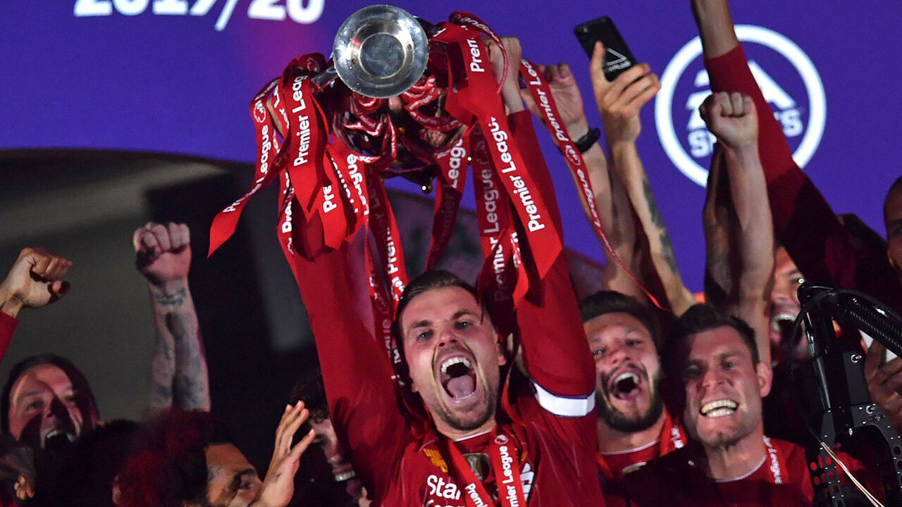 Liverpool's English midfielder Jordan Henderson (C) lifts the Premier League trophy during the presentation following the English Premier League football match between Liverpool and Chelsea at Anfield in Liverpool, north west England on July 22, 2020. - Liverpool on Wednesday lifted the Premier League trophy at the famous Kop stand at Anfield after their final home game of the season. With no fans able to attend due to the COVID-19 coronavirus pandemic, Liverpool said the idea for the trophy lift was to honour the club's fans, but Liverpool manager Jurgen Klopp urged fans to respect social distancing measures, after thousands gathered around the club's stadium and in the city centre following their coronation as champions last month.