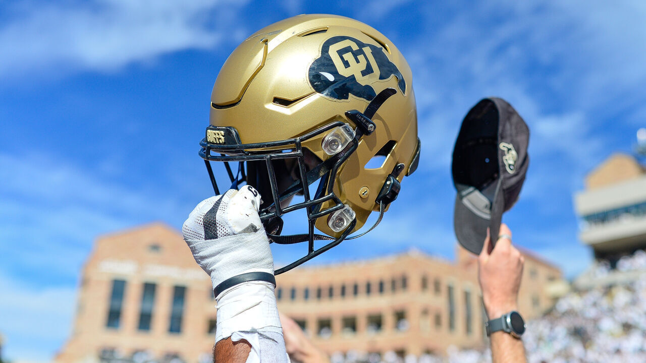 BOULDER, CO - OCTOBER 15: A Colorado Buffaloes helmet is held in the air as players celebrate on the field after an overtime win against the California Golden Bears at Folsom Field on October 15, 2022 in Boulder, Colorado.