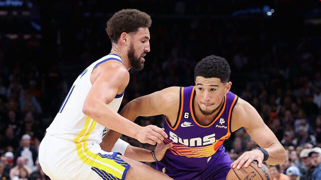 PHOENIX, ARIZONA - OCTOBER 25: Devin Booker #1 of the Phoenix Suns drives the ball against Klay Thompson #11 of the Golden State Warriors during the second half of the NBA game at Footprint Center on October 25, 2022 in Phoenix, Arizona. The Suns defeated the Warriors 134-105.