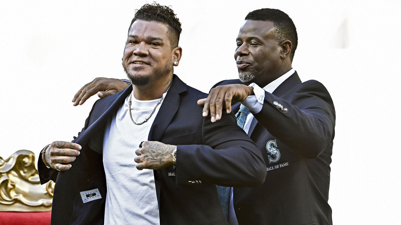 SEATTLE, WASHINGTON - AUGUST 12: MLB Hall Of Fame member Ken Griffey Jr. (R) helps Seattle Mariners great, Felix Hernandez, put on his new jacket during his Hall of Fame inductee ceremony before the game between the Seattle Mariners and the Baltimore Orioles at T-Mobile Park on August 12, 2023 in Seattle, Washington.