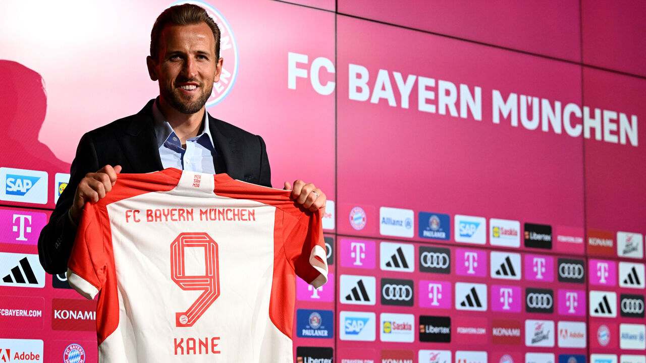 MUNICH, GERMANY - AUGUST 13: Harry Kane of FC Bayern München poses for a photograph whilst holding a FC Bayern München shirt, which reads "9 Kane", after speaking to the media during an official press conference announcing his signing with the club at Presse Club of Allianz Arena on August 13, 2023 in Munich, Germany. The English National forward signed a contract with the club until 2027.