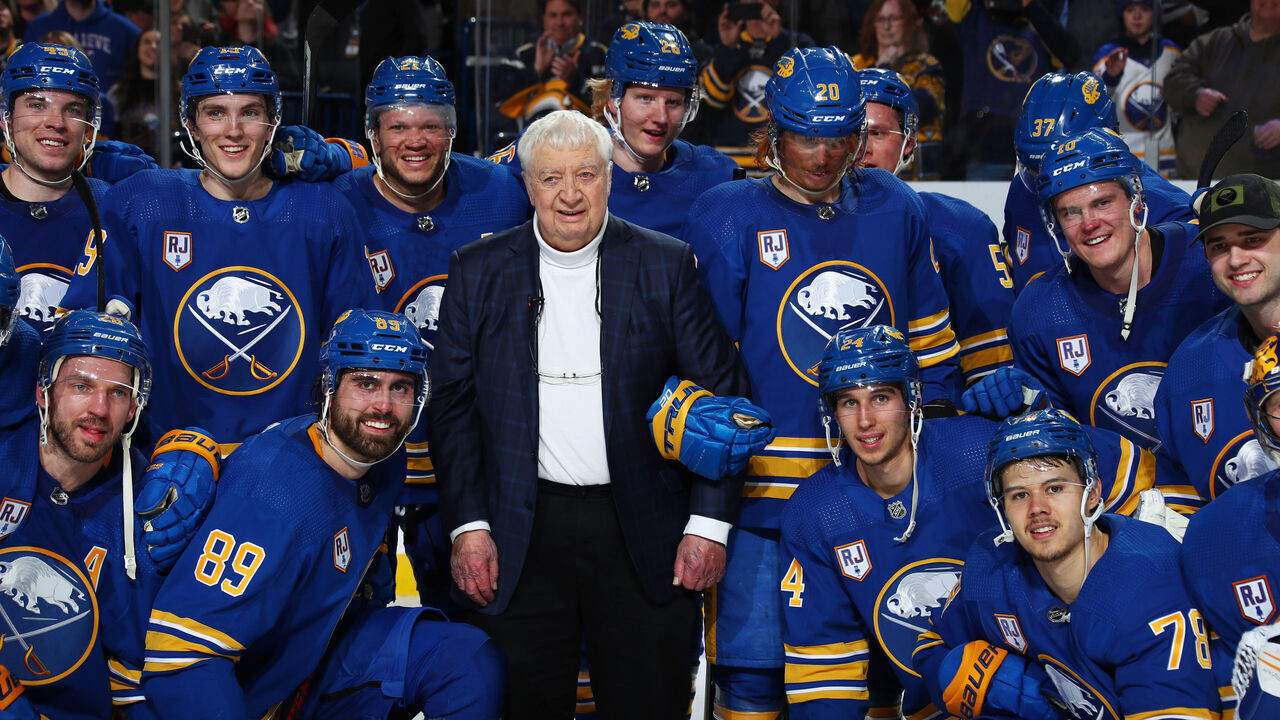 BUFFALO, NY - APRIL 1: Buffalo Sabres players pose with honored play by play announcer Rick Jeanneret following an NHL game against the Nashville Predators on April 1, 2022 at KeyBank Center in Buffalo, New York. Buffalo won, 4-3.