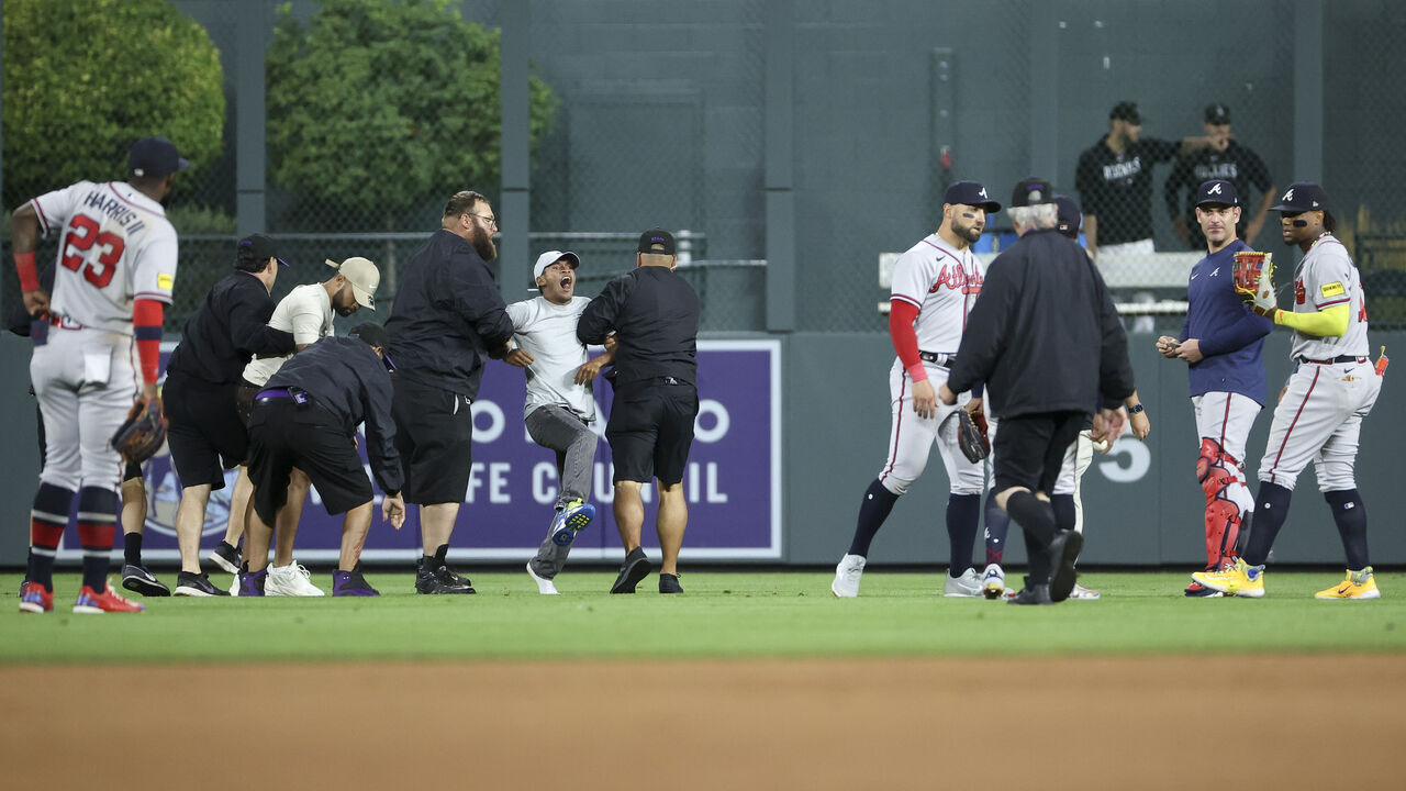 DENVER, COLORADO - AUGUST 28: A fan yells to Ronald Acuna Jr. #13 of the Atlanta Braves after running on the field and being apprehended by security during the game between the Colorado Rockies and the Atlanta Braves at Coors Field on August 28, 2023 in Denver, Colorado.