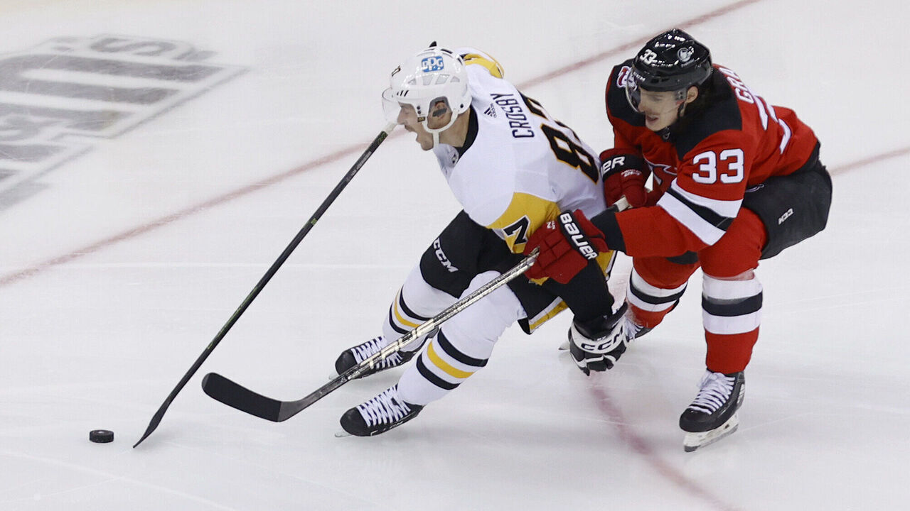 NEWARK, NEW JERSEY - JANUARY 22: Ryan Graves #33 of the New Jersey Devils chases Sidney Crosby #87 of the Pittsburgh Penguins for the puck during the 1st period at Prudential Center on January 22, 2023 in Newark, New Jersey.