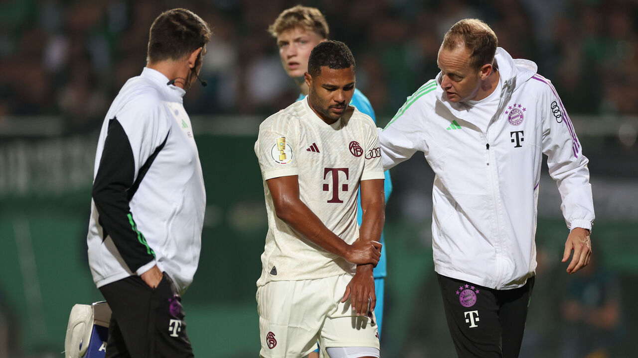 26 September 2023, North Rhine-Westphalia, Münster: Soccer: DFB Cup, Preußen Münster - Bayern Munich, 1st round at Preußenstadion. Munich's Serge Gnabry (M) has injured his arm in a duel and is escorted off the pitch. Photo: Friso Gentsch/dpa - IMPORTANT NOTE: In accordance with the requirements of the DFL Deutsche Fußball Liga and the DFB Deutscher Fußball-Bund, it is prohibited to use or have used photographs taken in the stadium and/or of the match in the form of sequence pictures and/or video-like photo series.