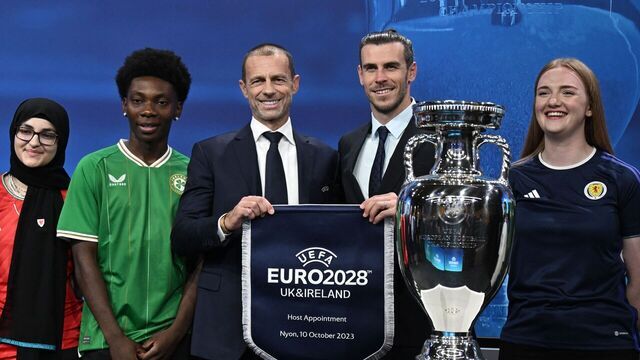 TOPSHOT - Welsh retired professional footballer, heading the delegation of UK and Ireland Gareth Bale (2ndR), flanked by UEFA president Aleksander Ceferin (C), poses next to the trophy with fans as they hold the pennant after United Kingdom and Ireland were elected to host the Euro 2028 fooball tournament during a ceremony at the UEFA headquarters in Nyon on October 10, 2023. Seven years after awarding Euro-2024 to Germany, UEFA announced on October 10, 2023 the hosts for the next two editions: The United Kingdom and Ireland are due to host the tournament together in 2028, followed by the unprecedented tandem of Italy and Turkey in 2032.