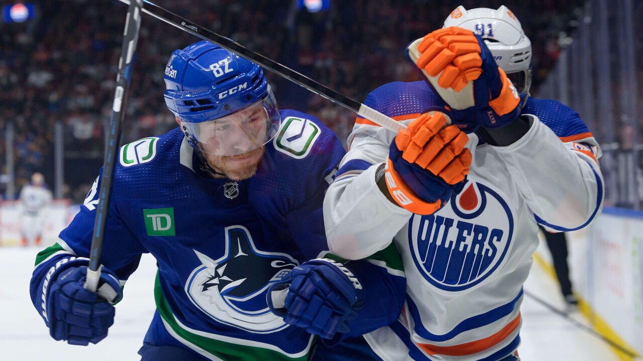 VANCOUVER, CANADA - OCTOBER 11: Evander Kane #91 of the Edmonton Oilers is checked by Ian Cole #82 of the Vancouver Canucks during the second period of their NHL game at Rogers Arena on October 11, 2023 in Vancouver, British Columbia, Canada.