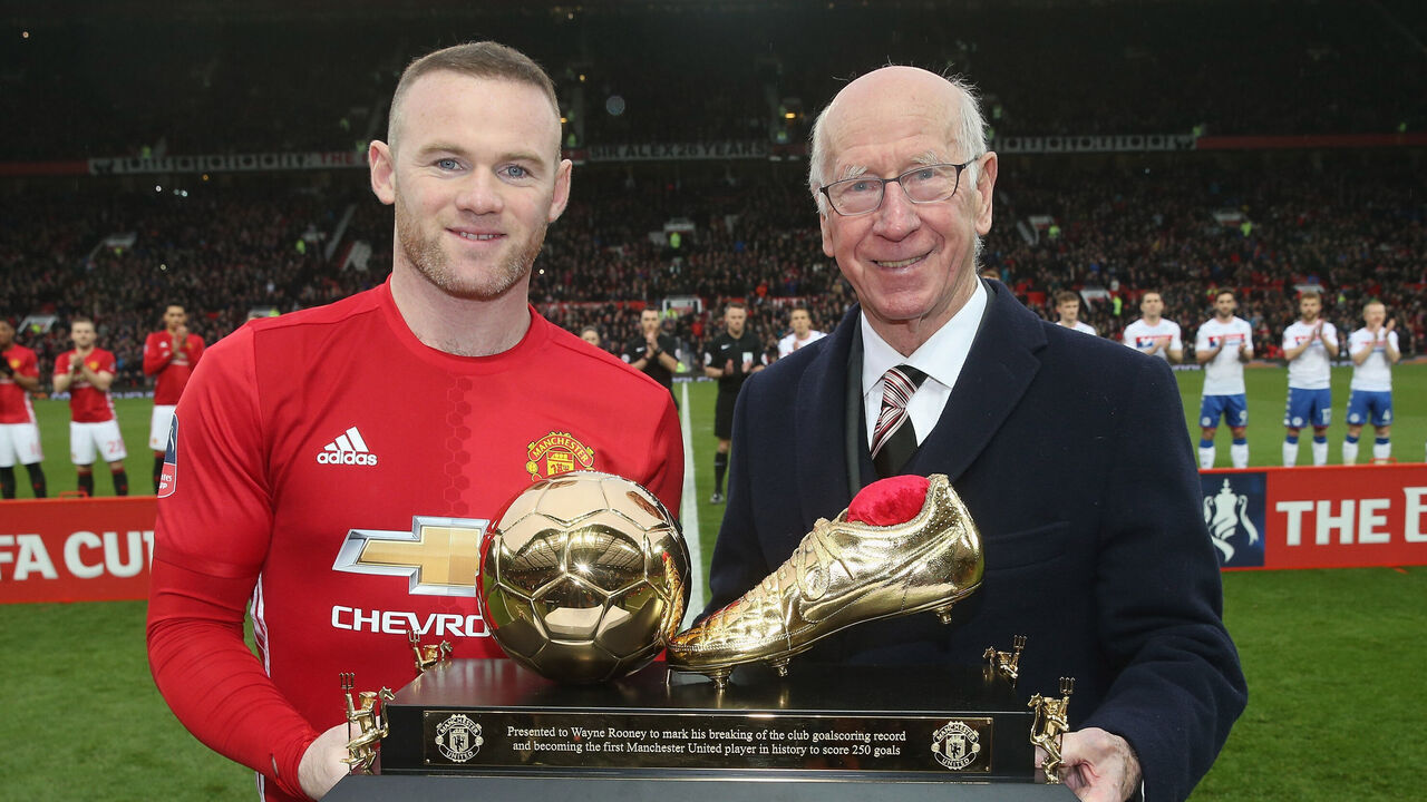 MANCHESTER, ENGLAND - JANUARY 29: Wayne Rooney of Manchester United is presented with a golden boot by Sir Bobby Charlton to mark his 250th Manchester United goal, which saw him break Charlton's club record, ahead of the Emirates FA Cup Fourth Round match between Manchester United and Wigan Athletic at Old Trafford on January 29, 2017 in Manchester, England.