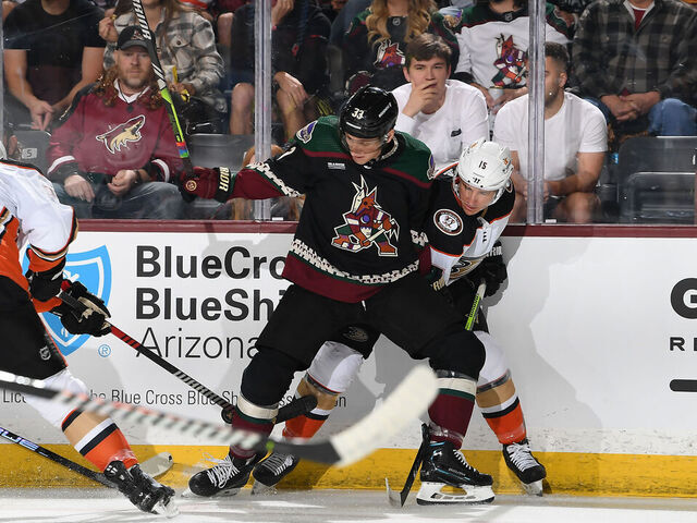 TEMPE, ARIZONA - OCTOBER 21: Travis Dermott #33 of the Arizona Coyotes battles for a loose puck with Ryan Strome #16 and Cam Fowler #4 of the Anaheim Ducks during the first period at Mullett Arena on October 21, 2023 in Tempe, Arizona.