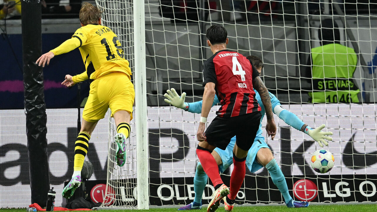 dpatop - 29 October 2023, Hesse, Frankfurt/Main: Soccer, Bundesliga, Eintracht Frankfurt - Borussia Dortmund, Matchday 9, at Deutsche Bank Park. Dortmund's Julian Brandt (l) scores the goal to equalize 3-3 against Frankfurt's Robin Koch (m) and goalkeeper Kevin Trapp. Photo: Arne Dedert/dpa - IMPORTANT NOTE: In accordance with the requirements of the DFL Deutsche Fußball Liga and the DFB Deutscher Fußball-Bund, it is prohibited to use or have used photographs taken in the stadium and/or of the match in the form of sequence pictures and/or video-like photo series.