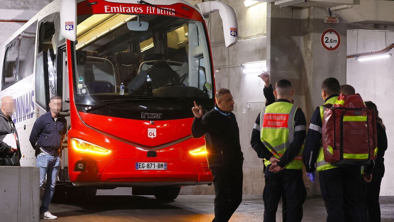 Firefighters stand next to Lyon's team bus, showing one window (L) completely broken and another damaged, after the bus was stoned as it entered the Stade Velodrome ahead of the French L1 football match between Olympique Marseille (OM) and Olympique Lyonnais (OL) at Stade Velodrome in Marseille, southern France on October 29, 2023. Lyon head coach Fabio Grosso was reportedly injured during the incident.