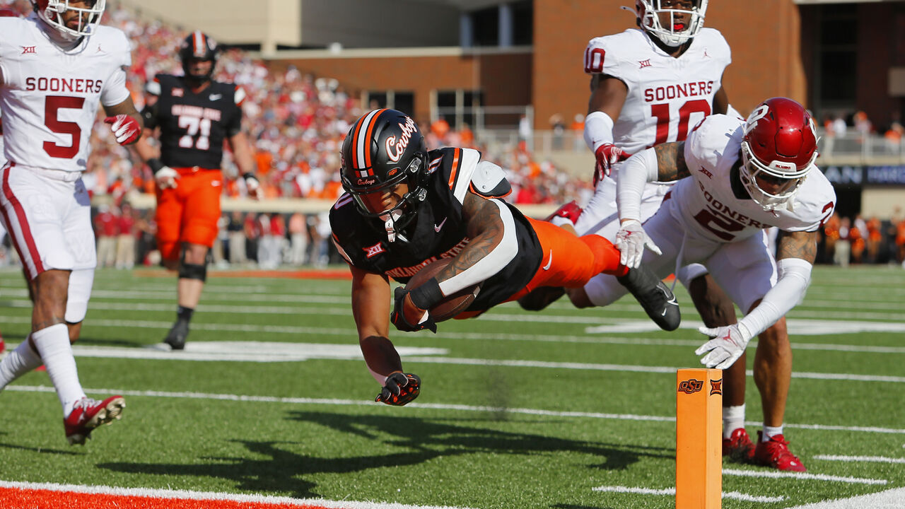STILLWATER, OK - NOVEMBER 4: Running back Ollie Gordon II #0 of the Oklahoma State Cowboys dives into the end zone on a 20-yard touchdown run against defensive back Billy Bowman Jr. #2 of the Oklahoma Sooners in the first quarter of Bedlam at Boone Pickens Stadium on November 4, 2023 in Stillwater, Oklahoma.