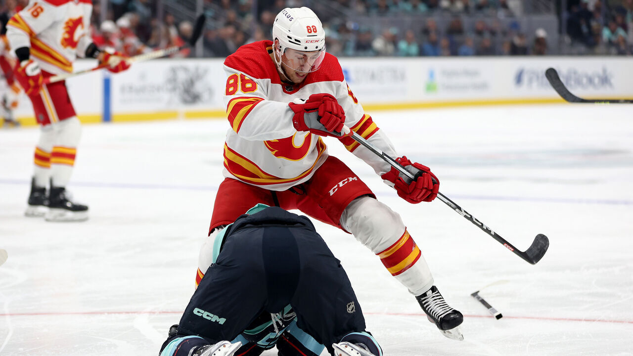 SEATTLE, WASHINGTON - NOVEMBER 04: Andrew Mangiapane #88 of the Calgary Flames plays the puck after checking Jared McCann #19 of the Seattle Kraken during the first period at Climate Pledge Arena on November 04, 2023 in Seattle, Washington.