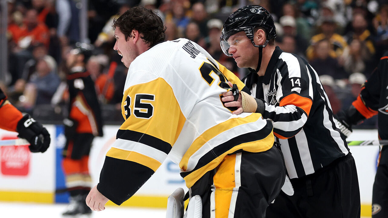 ANAHEIM, CALIFORNIA - NOVEMBER 07: Referee Trevor Hanson escorts Tristan Jarry #35 of the Pittsburgh Penguins off the ice after an injury during the second period of a game against the Anaheim Ducks at Honda Center on November 07, 2023 in Anaheim, California.