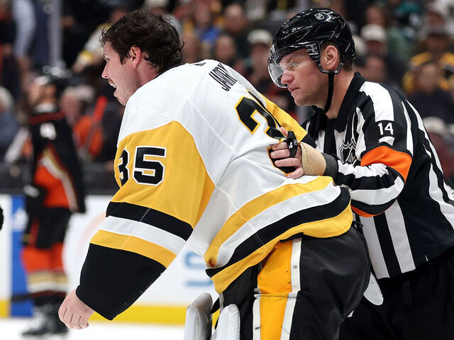 ANAHEIM, CALIFORNIA - NOVEMBER 07: Referee Trevor Hanson escorts Tristan Jarry #35 of the Pittsburgh Penguins off the ice after an injury during the second period of a game against the Anaheim Ducks at Honda Center on November 07, 2023 in Anaheim, California.